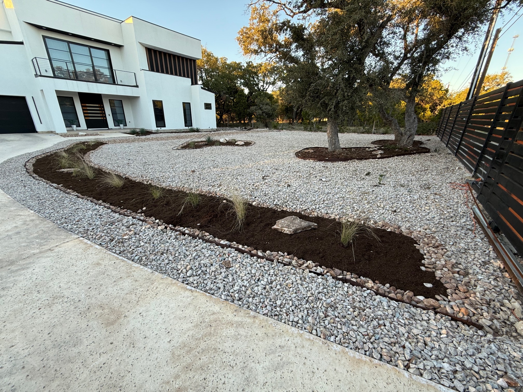 Modern xeriscape with river rock swale, mulched beds and ornamental grasses